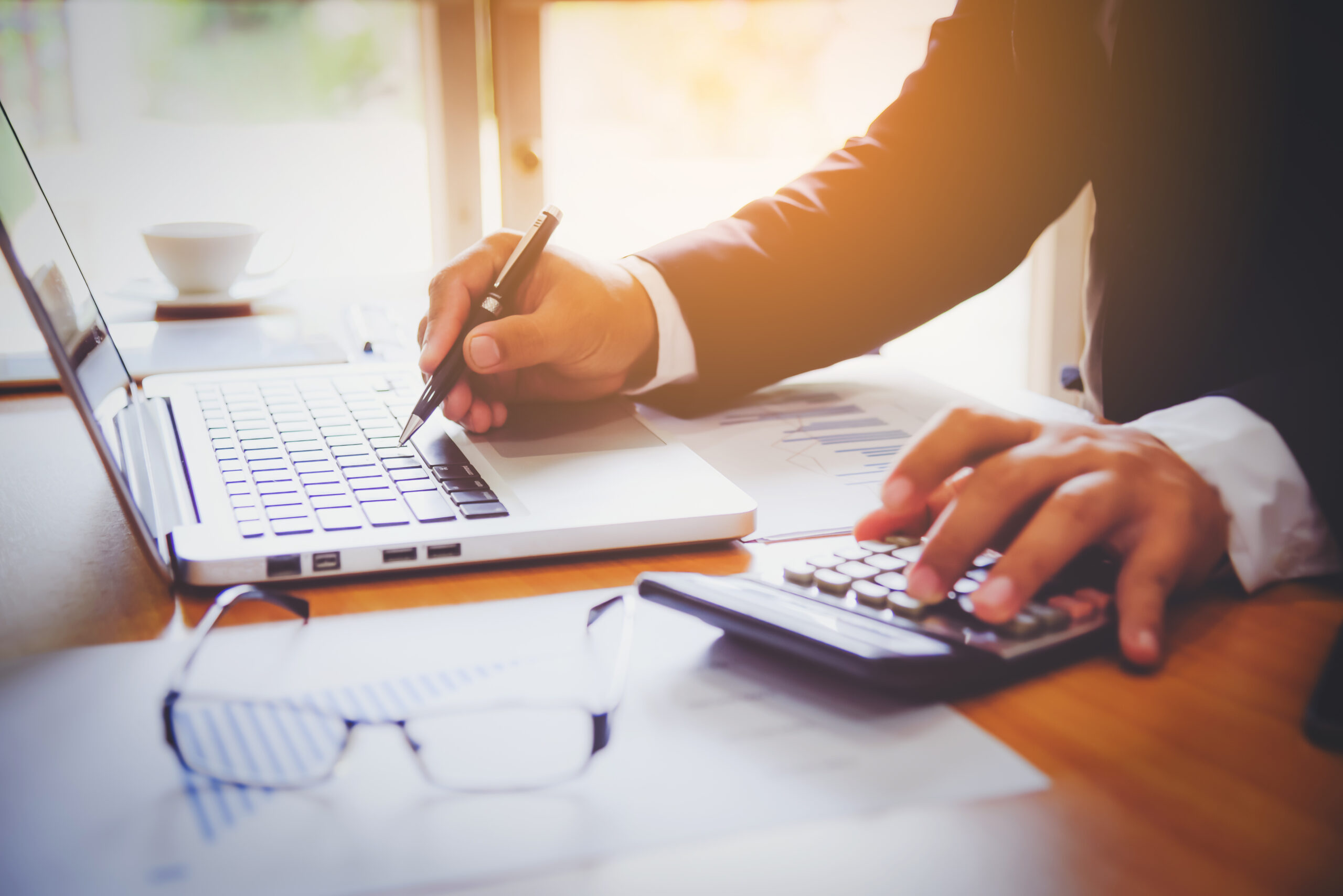 Profissional utilizando notebook, calculadora e relatórios financeiros para analisar cenários tributários, representando planejamento fiscal, tomada de decisão sobre o Simples Nacional Híbrido e consultoria contábil estratégica diante da Reforma Tributária.