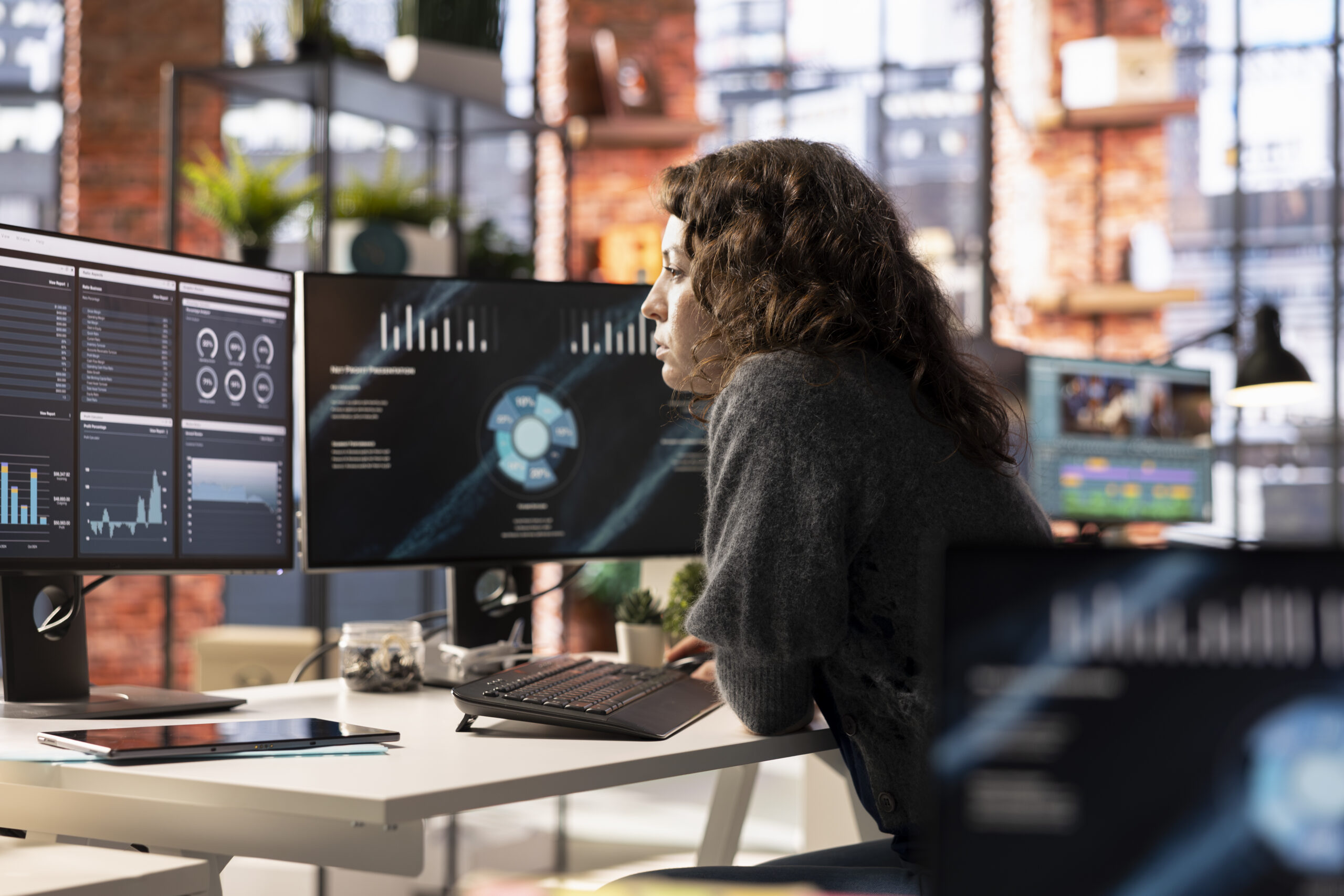 Profissional analisando dashboards e indicadores fiscais em múltiplos monitores em um escritório moderno, representando automação fiscal, monitoramento de dados, auditoria tributária e gestão de riscos em escritórios contábeis.