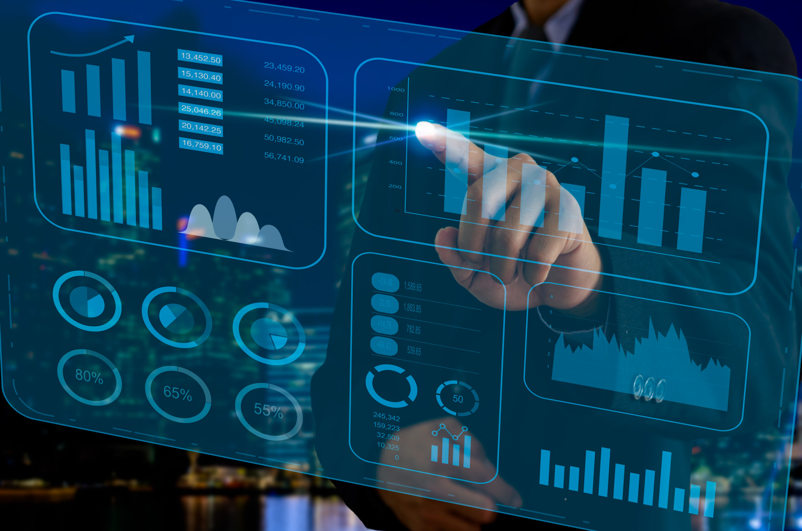 Profissional de terno toca um painel digital transparente com gráficos de barras, indicadores percentuais e dados financeiros, sobre um fundo noturno de cidade.