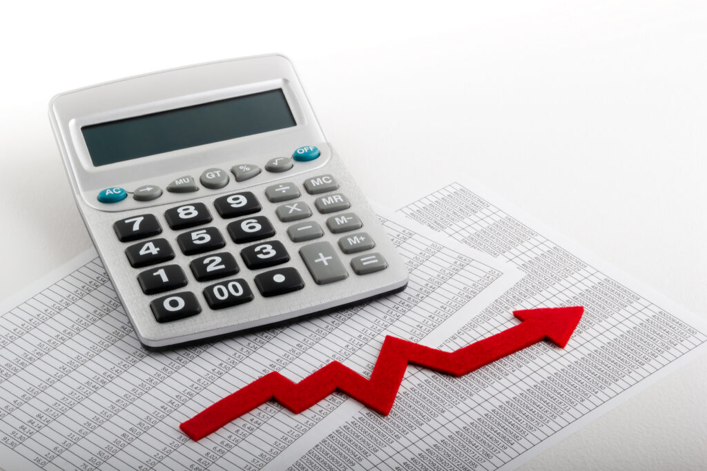Calculadora sobre planilhas de números com seta vermelha em alta, representando a alíquota da CBS em 2027