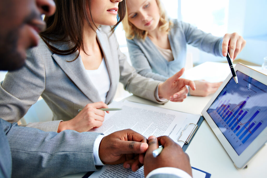 Equipe de profissionais analisando documentos e gráficos financeiros durante uma reunião de trabalho.